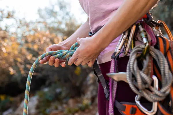 climber checks the knot before climbing. Close-up of a rock climber in harness and climbing equipment outdoors. Alpinism and rock climbing