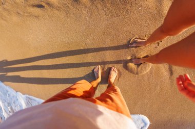 Kumsaldaki iki aşığın ayakları. Birbirine aşık bir çift güneşli bir yaz gününde sahilde yürür. Kız ve erkek arkadaşı sahilde eğleniyorlar..