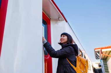 Sırt çantalı genç bir kız trene biniyor. Bir kız trenle seyahat eder. Yolculuğun tadını çıkarıyorum. Ulaşım, seyahat kavramı.