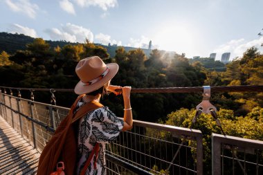 Şapkalı genç kız asma köprüde duruyor ve hayallerindeki uzaklığa bakıyor. yakın plan.