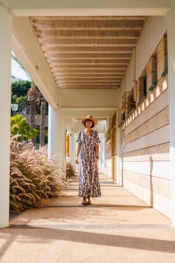 Açık havada, sokakta yürüyen, elbise ve şapka giymiş güzel esmer bir kadının uzun bir portresi. moda ve tarz kavramı.