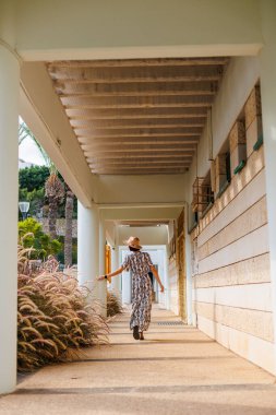 Açık havada, sokakta yürüyen, elbise ve şapka giymiş güzel esmer bir kadının uzun bir portresi. moda ve tarz kavramı.