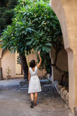 Tatilde bir turist. Özgürlük ve zevk ifade eden bir kadın. Beyaz elbiseli bir kız eski şehrin sokaklarında yürüyor. seyahat ve tatil.