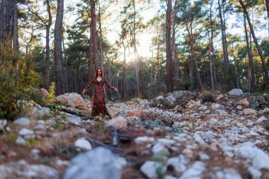 Genç ve güzel bir kadın güzel bir elbiseyle ormanda yürüyor. Denge, uyum ve sağlık kavramı. Kız doğayla baş başa..