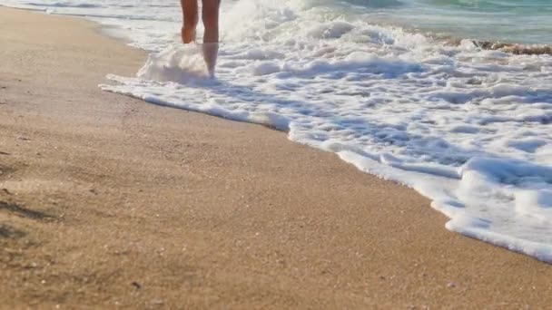 在海滩上放松一下 一个年轻的女人从水里走出来 沿着沙滩走着 女孩慢慢地沿着海滩走着 享受着假期 腿靠拢 — 图库视频影像