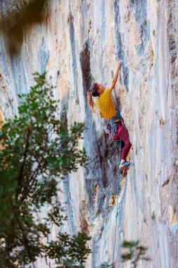 Climber zorlu tırmanma rotasını üstesinden geliyor. Bir kız kayaya tırmanıyor. Aşırı spor yapan kadın. Aşırı hobi