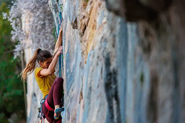 Climber overcomes challenging climbing route. A girl climbs a rock. Woman engaged in extreme sport. Extreme hobby