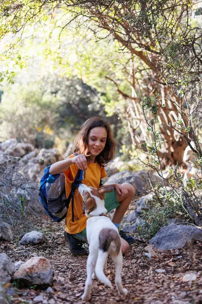 Little boy with a backpack on a hike. Healthy activity. a cheerful dog plays with a child during a hike, a child plays with a dog while trekking in the forest. in summer a child with a dog on a hike.