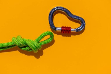 rope with a secure knot and a carabiner lies on a colored background. Equipment for rock climbing and mountaineering. reliable connection. Safety rope. concept of reliability and strength.