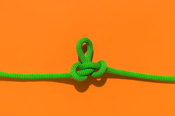 rope with a secure knot. concept of reliability and safety. climbing rope with a knot lies on a colored background. rope with a knot.
