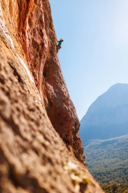 Bir kız kayalara tırmanıyor, bir kaya tırmanışçısı bir dağın arka planına tırmanıyor, sportif bir kız dağa tırmanıyor. Ekstrem. Türkiye.