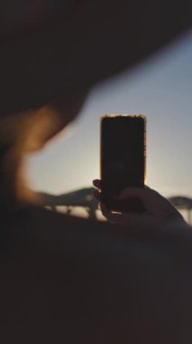 Dikey çekim. Kız telefonuyla fotoğraf çekiyor. Kumsalda dinlenmek..