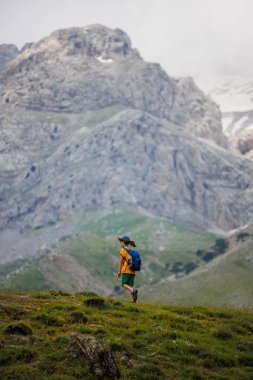 Sırt çantalı bir çocuk dağların arka planında yürüyüş yapıyor. Sırt çantalı çocuk gezgini, yürüyüş, seyahat, yaşam tarzı konsepti, arka planda dağlar, yaz tatili çocukları..