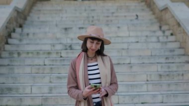 Genç bir kadın, eski şehri gezerken telefonuyla şehrin güzel manzarasının fotoğraflarını çekiyor. Genç, çekici, gülümseyen turist kız yeni bir şehri keşfediyor..