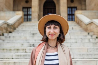 Şapkalı neşeli beyaz bir kadının portresi. İlginç yerlere seyahat et. Kameraya gülümseyen şapkalı şık bir kızın fotoğrafı..