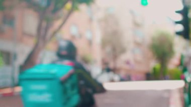 Binaları ve arabaları yolda olan sakin bir şehrin bulanık görüntüsü. Trafiği ve insanları olan şehir caddesi.