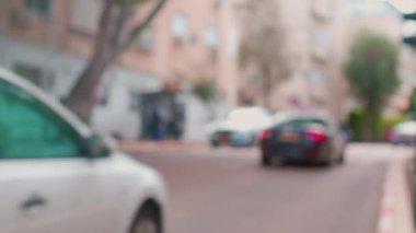 Binaları ve arabaları yolda olan sakin bir şehrin bulanık görüntüsü. Trafiği ve insanları olan şehir caddesi.