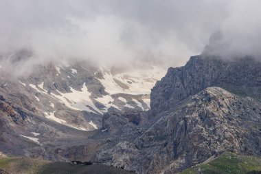 Karla kaplı dağların üzerinde bulutlar. Dağların ve sıradağların manzarası. Dağlarda kar