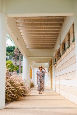 Elbiseli ve şapkalı genç kız caddede yürüyor. Sokakta yürü, güneşli hava, hafta sonu.