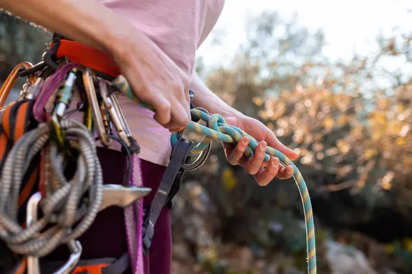 climber tying a knot before climbing. Close-up of a rock climber in harness and climbing equipment outdoors. Alpinism and rock climbing