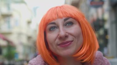 Şık giyinmiş, turuncu saçlı, gülümseyen ve sokakta gülen güzel bir kız. Mutlu kız..