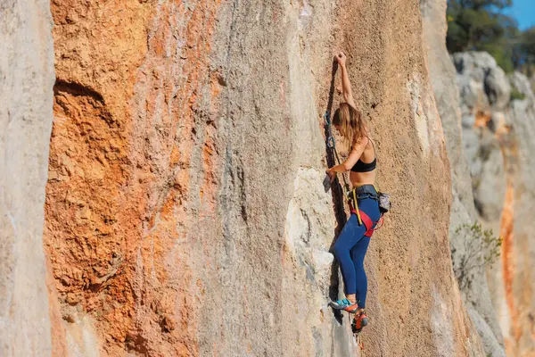 少女は岩に登った クライマーは岩を登る訓練をしている 強いアスリートは難しい登山ルートを克服する 最高の趣味 女性は自然の中でスポーツに行く ロイヤリティフリーのストック写真