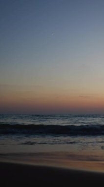 Dikey çekim. Yaz akşamından sonra deniz sahilinde yeni bir ay doğuyor. Güzel manzara. İsrail. Hayfa.