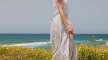 Yaz havası. Beyaz elbiseli genç bir kadın deniz kıyısında yürüyor. Kız denize bakmaktadır. Kumsalda dinlenmek..