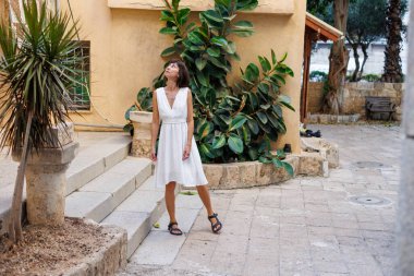 Tatilde bir turist. Bir kadın tatilde şehri gezmekten hoşlanır. Beyaz elbiseli bir kız eski şehrin sokaklarında yürüyor. seyahat ve tatil.