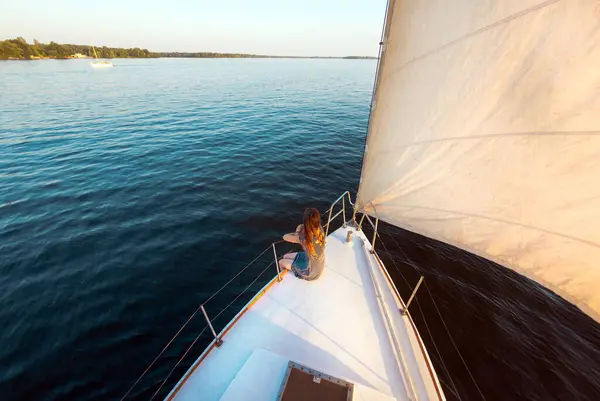 ヨットで旅を 白いヨットの西側に若い女の子が座っている 旅行中のプライバシー ストック画像
