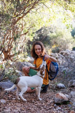 Little boy with a backpack on a hike. Healthy activity. a cheerful dog plays with a child during a hike, a child plays with a dog while trekking in the forest. in summer a child with a dog on a hike.