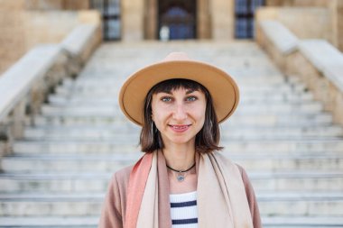 Şapkalı neşeli beyaz bir kadının portresi. İlginç yerlere seyahat et. Kameraya gülümseyen şapkalı şık bir kızın fotoğrafı..