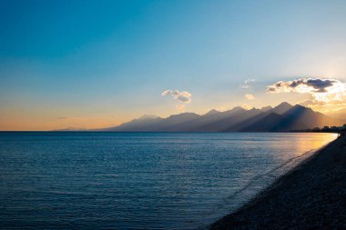 Akdeniz kıyılarının panoramik manzarası, gün batımında güzel dağlar. Panoramik günbatımı manzarası ve pitoresk plaj. Antalya. Türkiye.