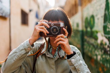 Kameralı kadın fotoğrafçı dışarıda fotoğraf çekiyor. Güzel bir kadın dışarıda analog kamera kullanarak fotoğraf çekiyor. Arap ülkelerine gitmek. seyahat ve tatil.