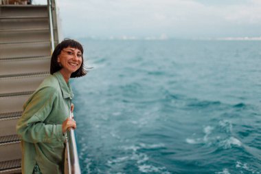 Kız bir yolcu gemisinin güvertesinde duruyor. Kız seyahat ediyor. Genç ve güzel bir esmer yat ile seyahat ediyor. seyahat ve macera.