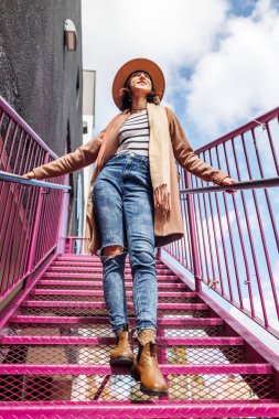 Şehirde şapkalı şık bir kız merdivenlerden aşağı iniyor. Moda tarzı.
