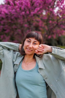 Mutlu bir kızın portresi. Genç bir esmer şehirde dururken mutlu bir şekilde gülümsüyor. Gömlekli, şık bir kız. Yaz Portresi