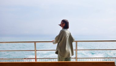 Genç bayan bir yolcu gemisinin güvertesinde duruyor ve yolculuğun tadını çıkarıyor. Yatta, tatilde ve seyahatte olan bir kadın. Genç ve güzel bir esmer yat ile seyahat ediyor. seyahat ve macera.