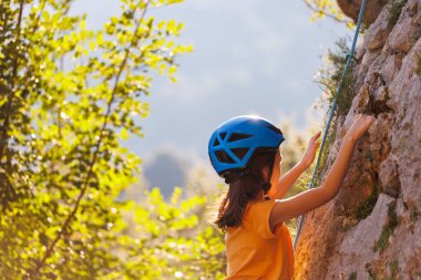 Dağcı çocuk. Çocuk yaz kampında kaya tırmanışı eğitimi alıyor. Doğada spor. kaya tırmanışı