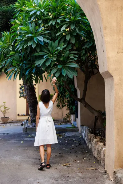 Tatildeki kız. Özgürlük ve zevk ifade eden bir kadın. Beyaz elbiseli bir kız eski şehrin sokaklarında yürüyor. seyahat ve tatil.