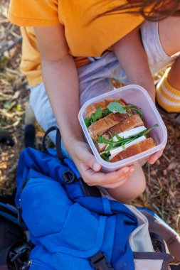 Çocuk bir beslenme çantası alır ve yürüyüşe çıkmaya hazırlanır. Sokaktaki yemek. Bir çocukla yürüyüş. seyahat ve macera.