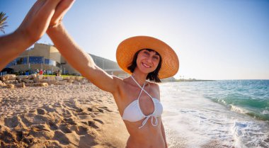 Şapkalı ve bikinili güzel bir kız arkadaşına beşlik çakıyor. Arkadaşlarla denizde tatil. Deniz kıyısında seyahat ederken arkadaşlarla buluşmak. Genç bir kız seyahat ederken gülümser.