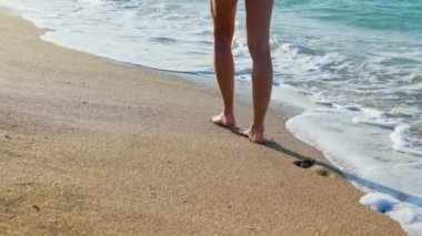 Sahilde bir gün. Bir kız kumsalda yürüyor. Bacaklar yakın. Mutlu kadın plajda dinlenmeyi sever. Sahildeki kız..