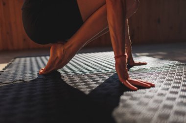 Kız yoga yapıyor. Doğadaki sınıf. Kadınların elleri aşağı iner ve avuçlarıyla halıya dokunur. Eller ve ayaklar yoga minderine yakın çekim. sakinlik ve meditasyon kavramı.