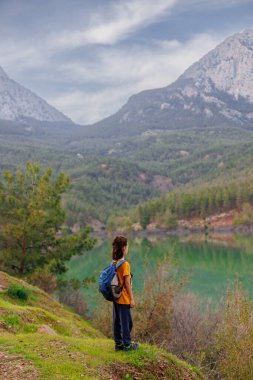 Yaz kampı. Sırt çantalı bir çocuk güzel bir dağ gölüne bakıyor. Bir dağ gölünün yanında yürüyüş. Çocuklarla Tatil