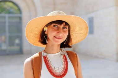 Şapka ve boncuklu genç bir kızın portresi. Modaya uygun aksesuarlar. Model kameraya bakar ve gülümser..