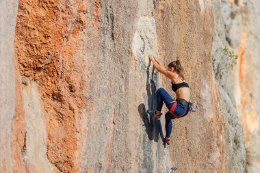 Kız kayaya tırmandı. Dağcı kayaya tırmanma eğitimi alıyor. Güçlü bir atlet zor bir tırmanış rotasının üstesinden gelir. Olağanüstü bir hobi. Bir kadın spor için doğaya gider..