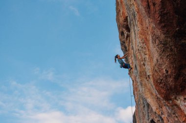 Bir kız dağcının silüeti. Kaya tırmanışçısı kız bir kayaya tırmanıyor. Spor ve açık hava eğlencesi