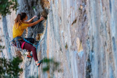Kız kayaya tırmandı. Dağcı doğal arazide antrenman yapar. Olağanüstü bir spor. Açık hava aktiviteleri. Bir kadın zor bir dağ tırmanışının üstesinden gelir.