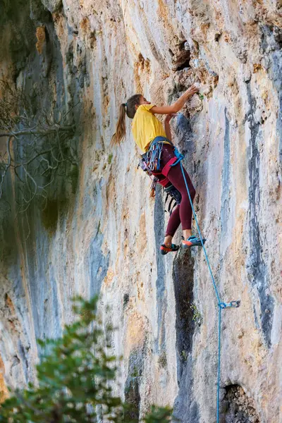 Dağcı kız. Bir olimpiyat sporu olarak kaya tırmanışı. Güçlü kız. Bir kadın doğada spor yapar. Bir kız kayaya tırmanıyor..